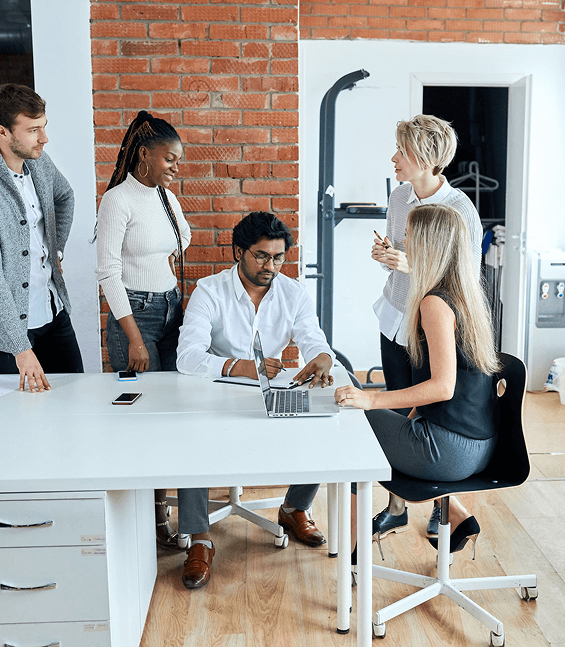 Grupo de colaboradores reunidos em uma mesa de escritório debatendo sobre os riscos psicossociais